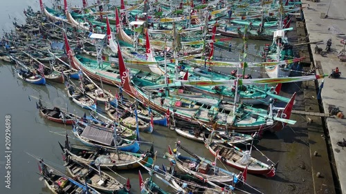 Tilted aerial footage of colorful fishing fleet of traditional vessels in Muncar harbor East Java, Indonesia photo