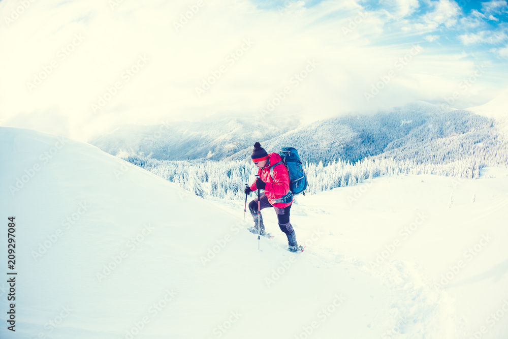 A man in snowshoes in the mountains.