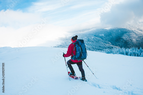 A man in snowshoes in the mountains.