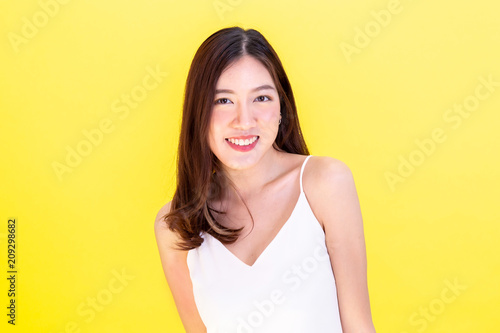 Portrait of attractive Asian smiling woman showing cute expression and posture with isolated on yellow background