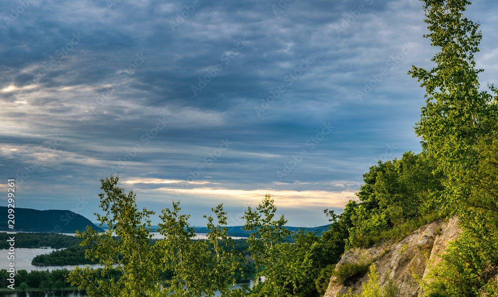 Naklejka premium Panoramic landscape with green forest, birch trees, Volga river embankment and hills during sunset in park near Samara city, Russia