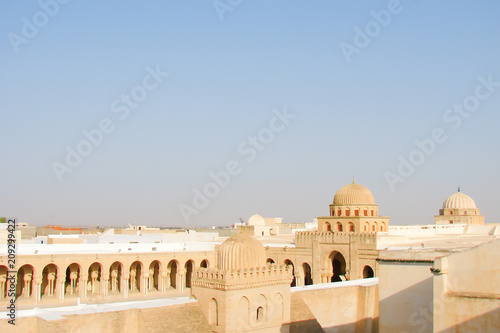 an ancient mosque and blue sky, domes and walls of sandstone, view from the wall, Tunisia