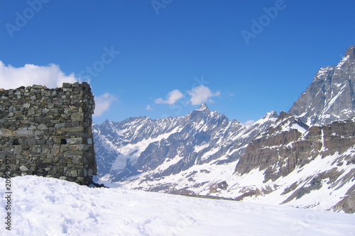 sunny day in Dolomite Alps, peaks, snowdrift and stone wall