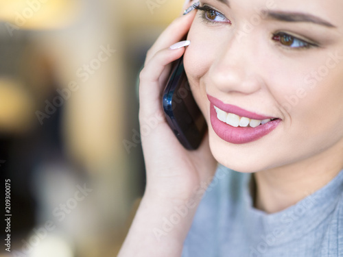 Portrait of a smiling woman talking on her mobile phone, looking away.
