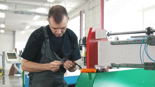 Electrician in overalls is working with energy panel and machinery equipment on plant photo