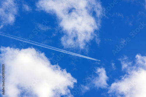 White clouds and an airplane trail in a blue sky