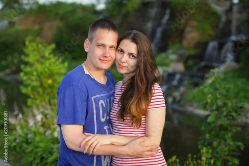 beautiful couple standing hugging each other at sunset on the nature near the waterfall, selective focus