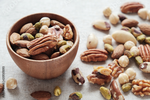 Mixed nuts in wooden bowl, healthy fat and protein food, vegan, plant based diet, natural sources of tryptophan for getting good sleep and relaxation