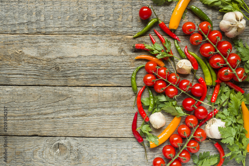 mixture of chili pepper cherry tomato on a branch garlic and other spices on a wooden copy space background mixture of chili pepper cherry tomato on a branch garlic and other spices on a wooden copy space background