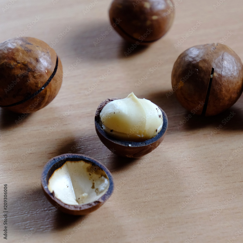 Obraz premium Macadamia nuts in shell on wooden table
