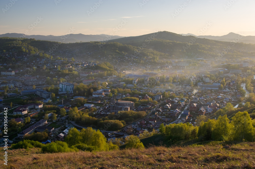 Fototapeta premium Green mountain landscape with illuminated sunset light town village valley among hills