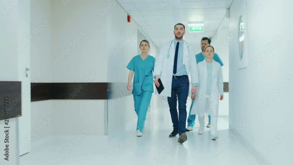Team of Doctors, Surgeons and Nurses Walk Through Busy Hospital Hallway, They Talk about Patients, Forthcoming Surgeries and Saving Lives. Shot on RED EPIC-W 8K Helium Cinema Camera. Team of Doctors, Surgeons and Nurses Walk Through Busy Hospital Hallway, They Talk about Patients, Forthcoming Surgeries and Saving Lives. Shot on RED EPIC-W 8K Helium Cinema Camera.