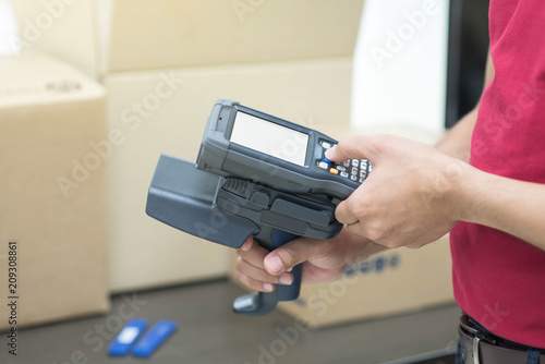 Hands holding portable barcode scanner in warehouse