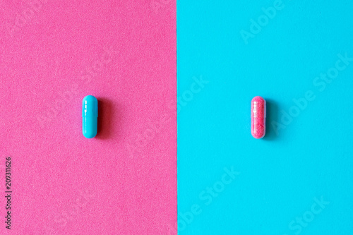 Pink and blue capsules, pills isolated on bicolor pink and blue colored background. Medication and prescription pills minimal coloured flat lay with copy space. Pharmaceutical industry minimal concept