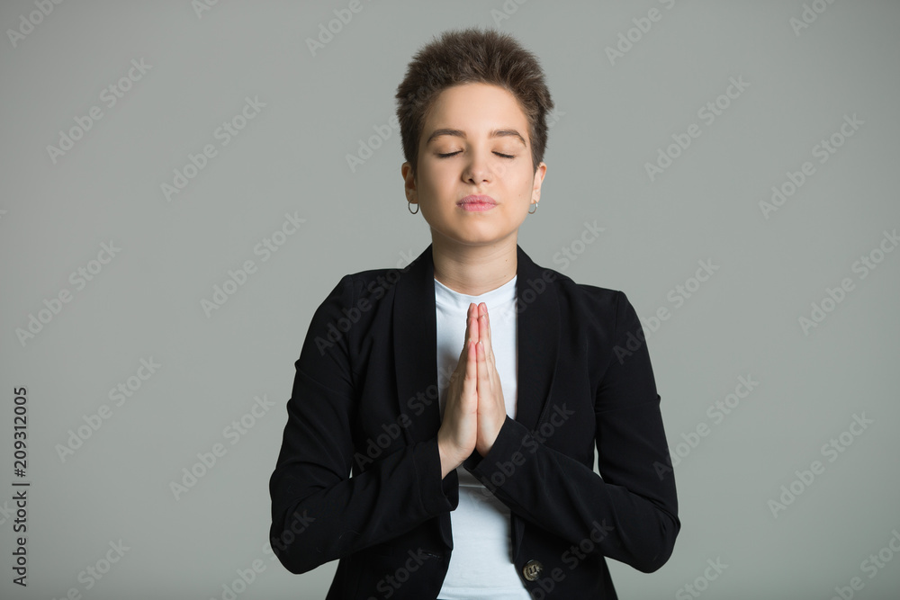 young beautiful girl in a black jacket with a short haircut on a gray background with closed eyes young beautiful girl in a black jacket with a short haircut on a gray background with closed eyes