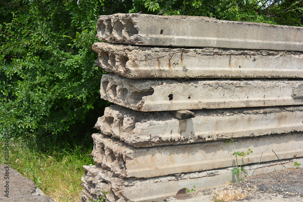 Reinforced concrete slabs for covering the floors of the house, the skeleton of the old collapsed species against the background of a green tree Reinforced concrete slabs for covering the floors of the house, the skeleton of the old collapsed species against the background of a green tree