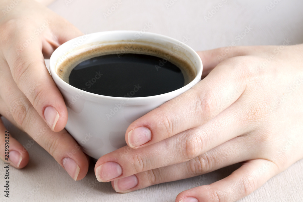 Hands holding a Cup of coffee on a bright table. Hands holding a Cup of coffee on a bright table.