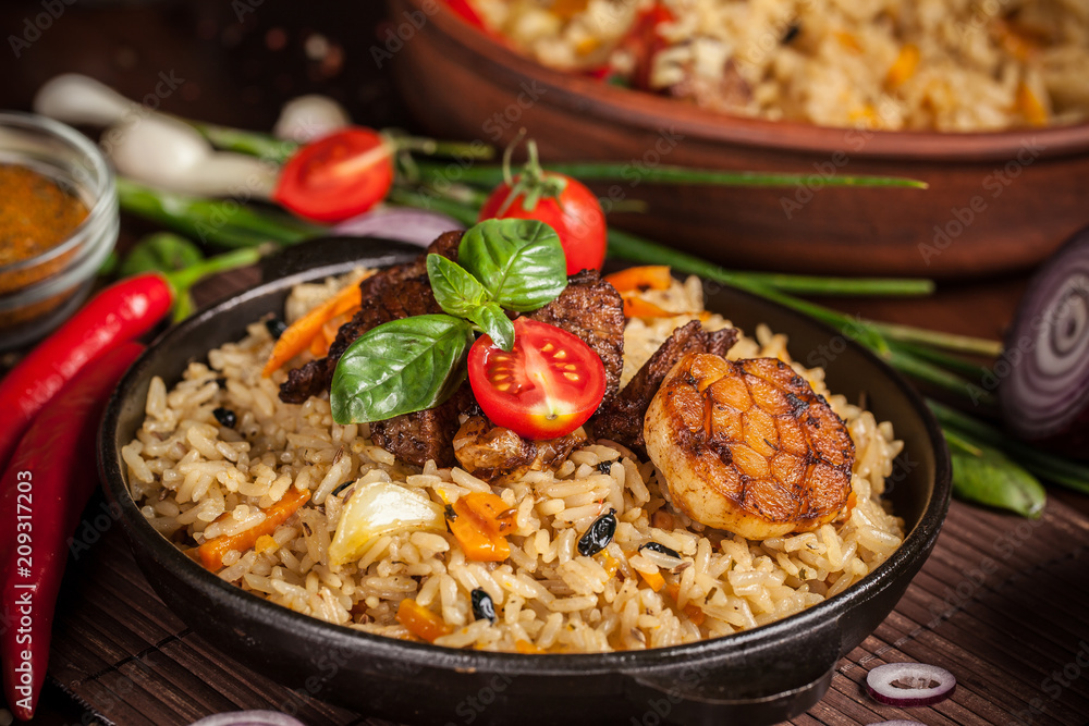 The concept of oriental cuisine. Homemade Uzbek pilaf from lamb served in cast iron cookware. Copy space. The concept of oriental cuisine. Homemade Uzbek pilaf from lamb served in cast iron cookware. Copy space.