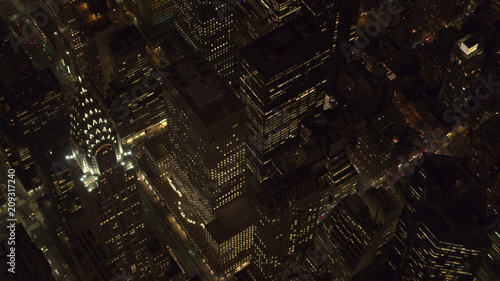AERIAL: Lit Chrysler Building and Midtown Manhattan streets shining at night