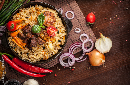 The concept of oriental cuisine. Homemade Uzbek pilaf from lamb served in cast iron cookware. Copy space. photo