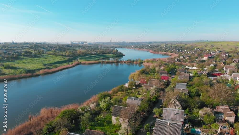 The flight of drones over country houses in the hills on the shore of the pond early in the morning at dawn. Flight over the water at a bird's eye view. Aerial view 4K The flight of drones over country houses in the hills on the shore of the pond early in the morning at dawn. Flight over the water at a bird's eye view. Aerial view 4K