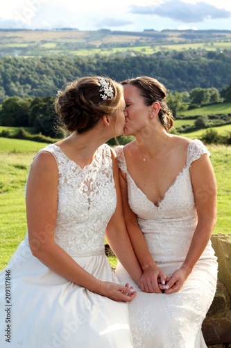 Same sex brides kissing on their wedding day in a rural marriage in the Yorkshire countryside 