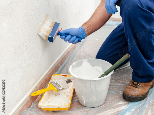 House painter at work painting a wall with a brush