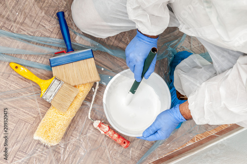 House painter at work prepares white paint photo