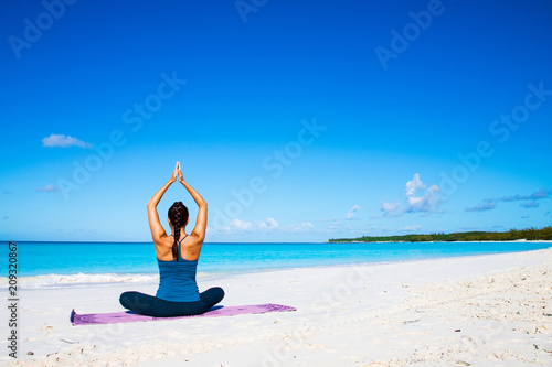 Beautiful young woman practicing yoga on the beach on Bahamas iseland.