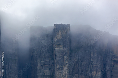 Leinwand Poster View of Preikestolen steep cliff in fog from the Lysefjorden, Rogaland, Norway