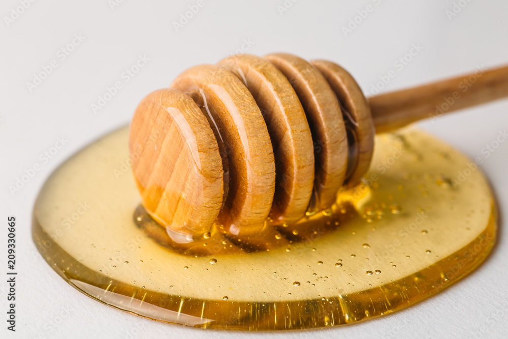 Honey dripper on white background with spot of fresh organic honey, macro Honey dripper on white background with spot of fresh organic honey, macro