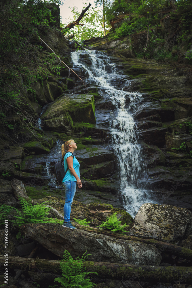 Girl traveler near a forest waterfall. Girl traveler near a forest waterfall.