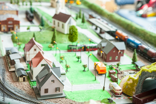 A breadboard model of a railway with a locomotive, wagons, trees, buildings, lawns. View from above.