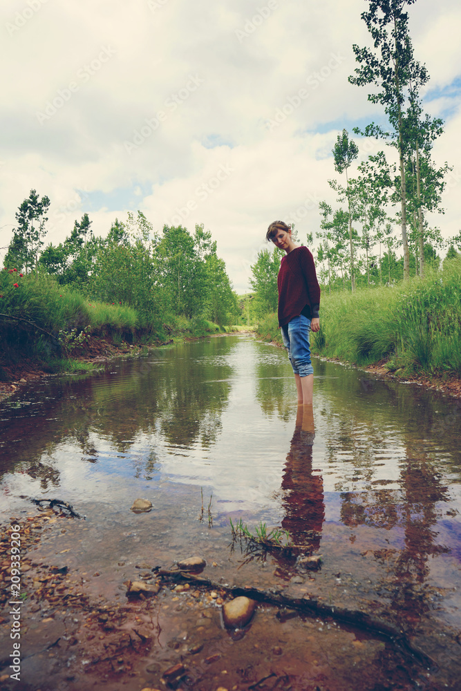 Mujer joven en mitad de la naturaleza, junto a un improvisado río de lluvia Mujer joven en mitad de la naturaleza, junto a un improvisado río de lluvia