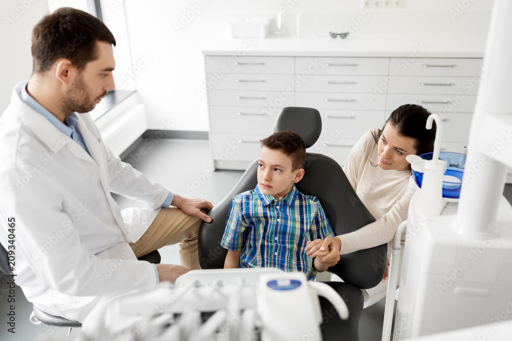 Obraz premium medicine, dentistry and healthcare concept - mother and son visiting dentist at dental clinic