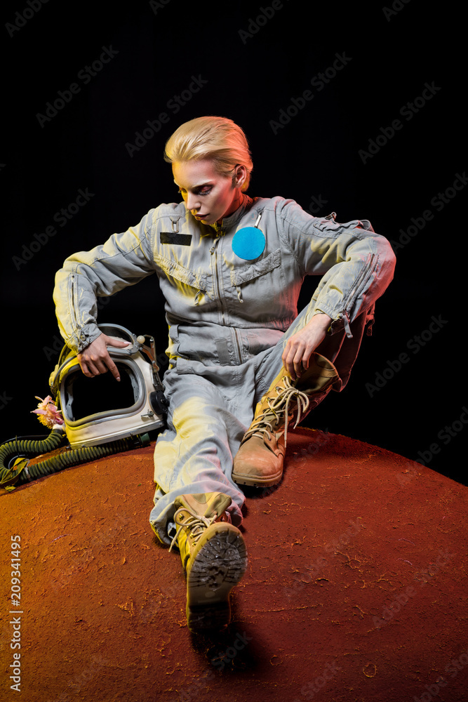 beautiful astronaut in spacesuit with helmet sitting on planet
