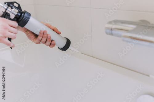 hands of man putting a silicon with a silicon tube in bathroom