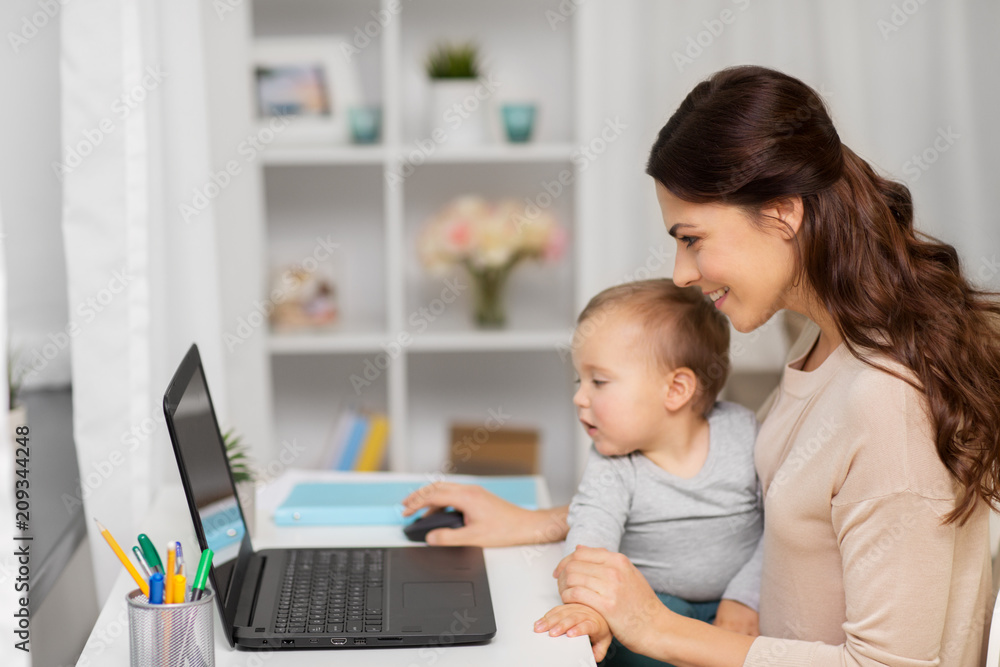 motherhood, multi-tasking, family and people concept - happy mother with baby and laptop working at home motherhood, multi-tasking, family and people concept - happy mother with baby and laptop working at home