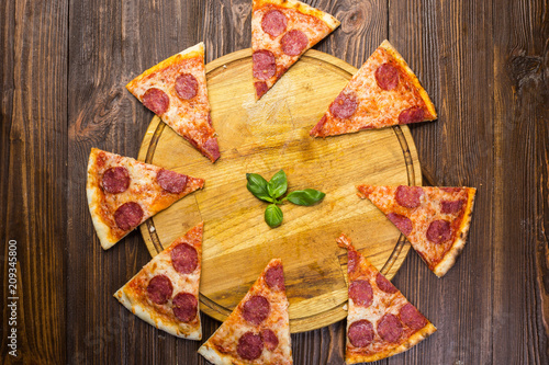 Pizza pepperoni with mozzarella cheese, salami and arugula on wooden background