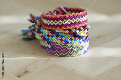 Handmade homemade colorful natural woven bracelets of friendship isolated on light blue background, pile of colorful handcrafts