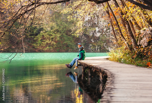 Father with son sit on bridge near the mountain lake, autumn sunny afternoon © Soloviova Liudmyla