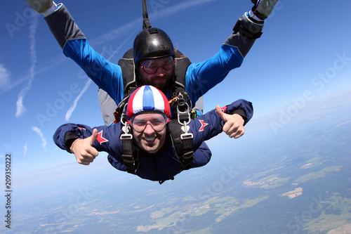 Skydiving. Two men are flying in the blue sky.