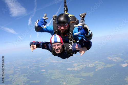 Skydiving. Two men are flying in the blue sky.
