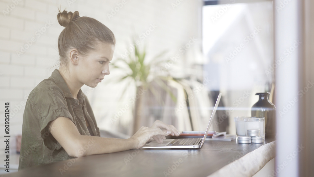 A young pretty serious concentrated girl dressed in a green shirt with a laptop sitting at a table A young pretty serious concentrated girl dressed in a green shirt with a laptop sitting at a table
