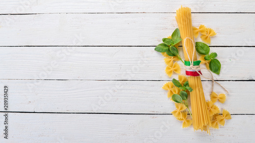 Italian cuisine. Dry pasta and basil. On a wooden background. Top view. Copy space.
