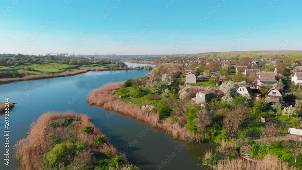 The flight of drones over country houses in the hills on the shore of the pond early in the morning at dawn. Flight over the water at a bird's eye view. Aerial view 4K The flight of drones over country houses in the hills on the shore of the pond early in the morning at dawn. Flight over the water at a bird's eye view. Aerial view 4K