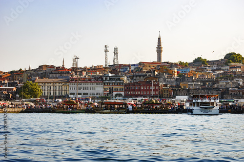 Moored ships, cafes, restaurants, pedestrian walkways and street vendors can be seen on the shore near Galata Bridge that crosses the Golden Horn, Istanbul, Turkey. City view