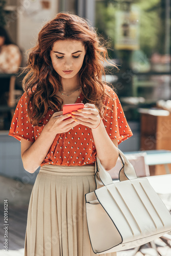 Fotografie portrait of young stylish woman using smartphone on street