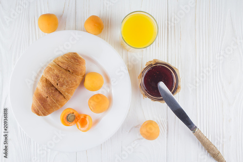 croissant, apricot, jam and juice for breakfast
