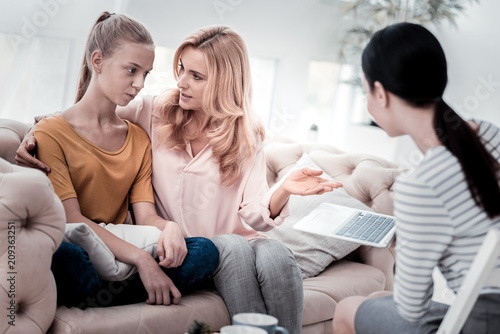 Share your feelings. Excited mother sitting closely to her daughter and talking while experienced psychologist listening to them